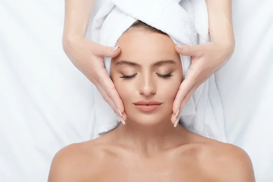 "A woman receiving a Harmony Facial treatment, with a device gently applied to her face."