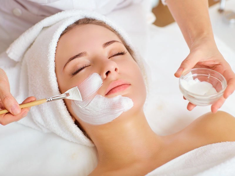 Fire & Ice facial treatment with a therapist applying a mask to a client's face in a spa setting.