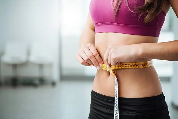 "A person standing on a digital scale, with a pair of running shoes and a water bottle beside them, symbolizing a commitment to fitness and weight loss."