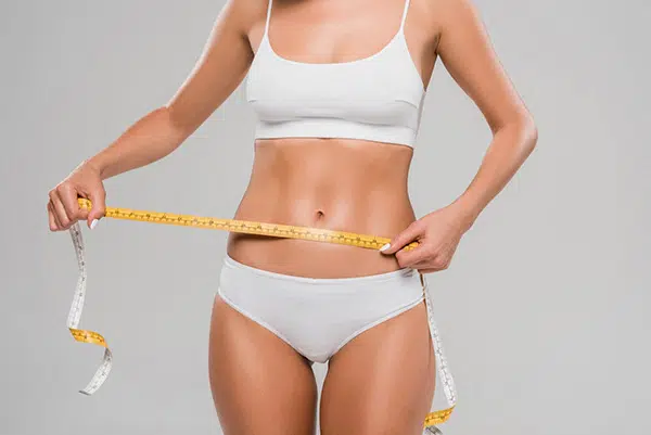 A woman jogging in the park, representing weight loss and a healthy lifestyle.